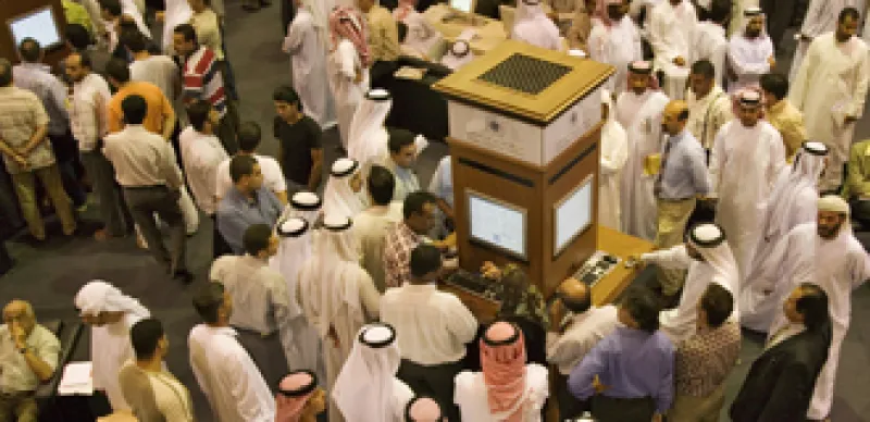 Investors at the Dubai Financial Market, the local Stock Exchange,  gather round the display showing the latest prices.  Dubai. United Arab Emirates. 